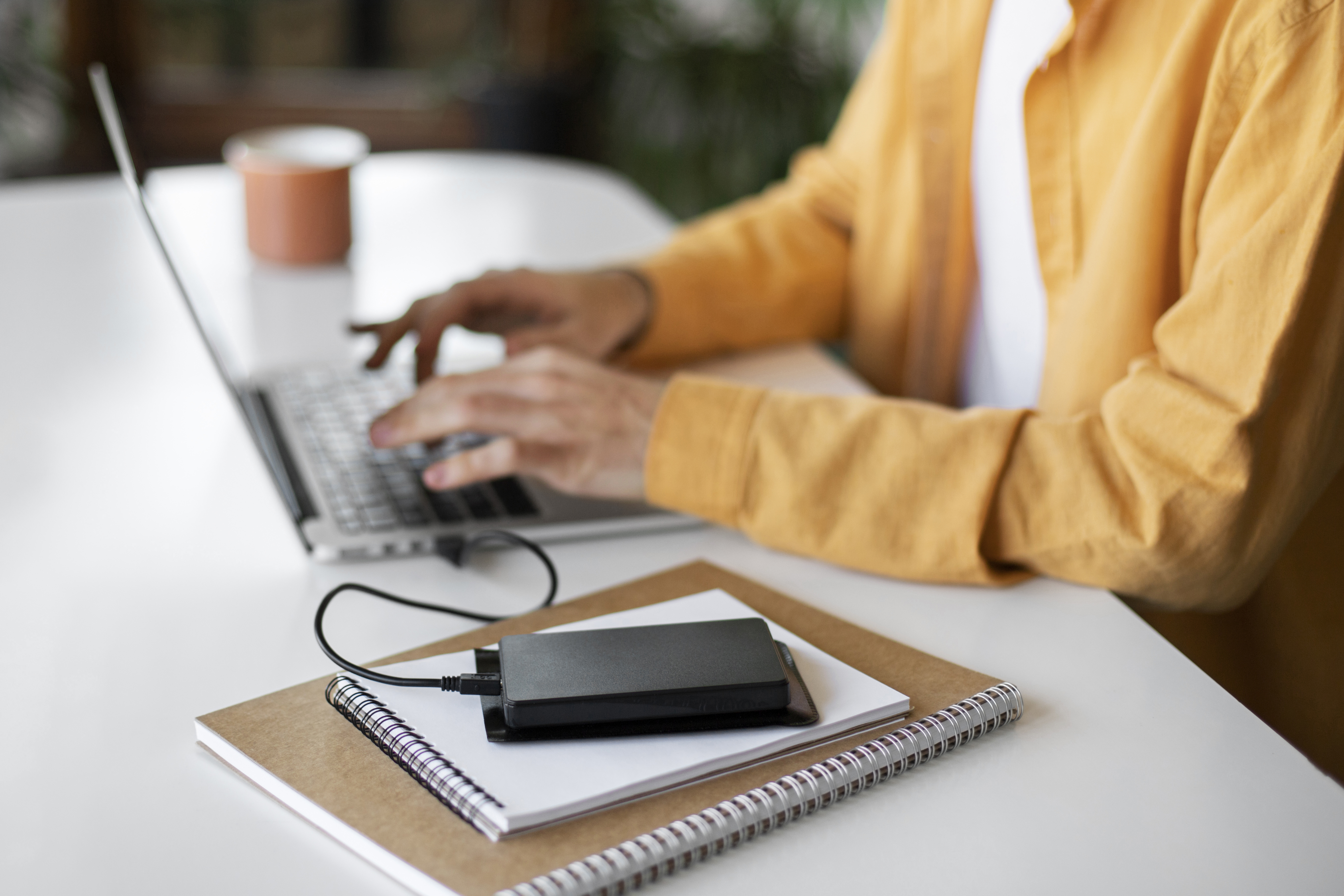 Disque dur externe portable posé sur un bureau à côté d'un ordinateur