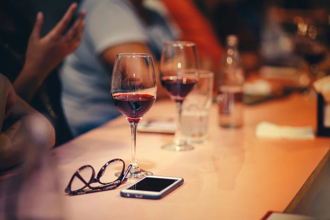 Bouteille de Beaujolais Nouveau 2025 servie à table avec des verres de vin rouge