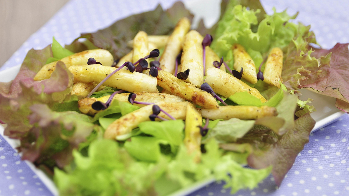 Racines de salsifis frais avec leur peau claire sur une table de cuisine