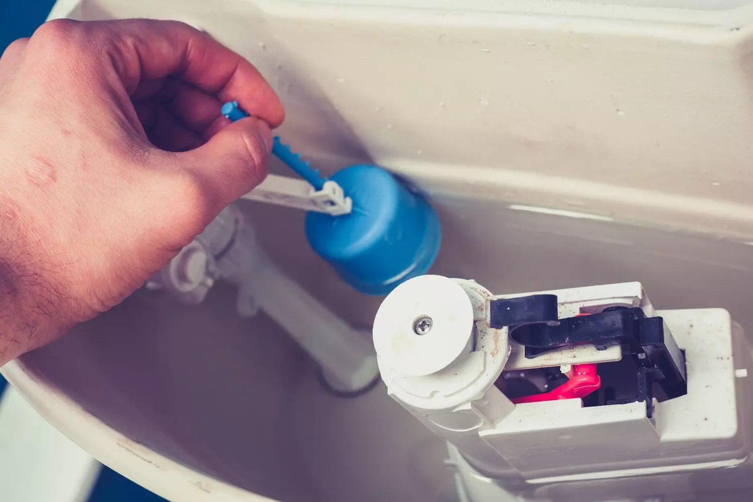 Réservoir de toilettes ouvert montrant le mécanisme d'une chasse d'eau qui fuit
